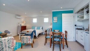 A compact bedroom with a bed, bedside table, and a small seating area with a chair and a table.