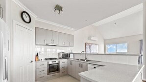A modern kitchen with white cabinetry, a built-in oven, a microwave, and a stainless steel sink. - Flinders View Beach House (4Bed 2Bath) - Flinders View Beach House - Executive Holiday Home (Augusta)