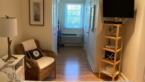 A hotel room with a bed, a chair, a TV on a stand, and a window with blinds.