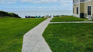A pathway leading to a building with a view of the sea.