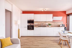 Eine moderne Küche mit weißen Schränken, einer Holz Arbeitsplatte und einem Essbereich mit weißem Tisch und Stühlen.