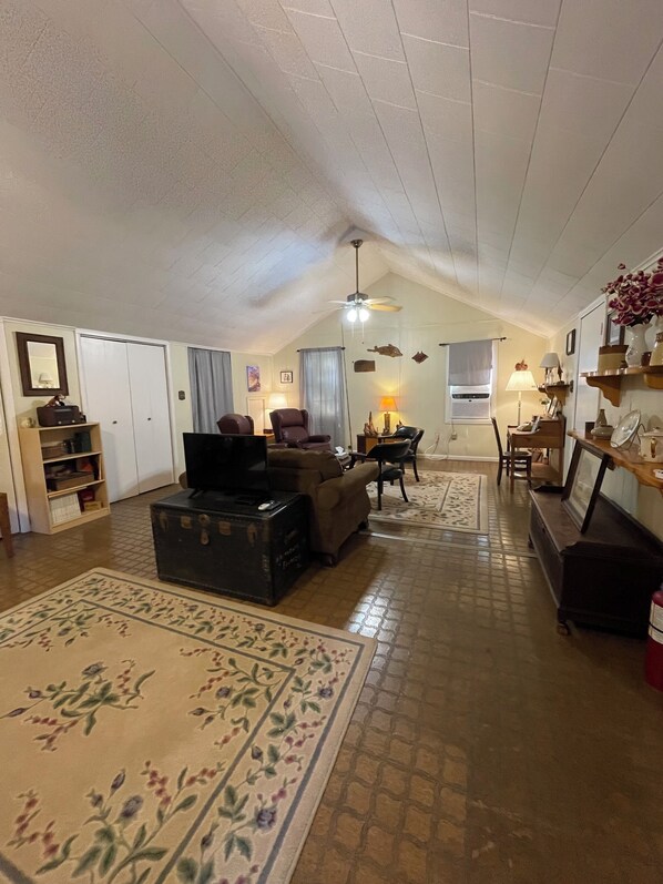 A spacious living room with a high ceiling, a sofa, a coffee table, and a fireplace.