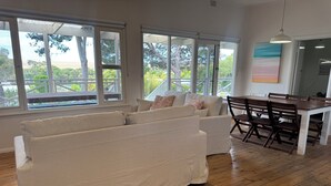 Een ruime woonkamer met een grote bank, houten vloeren en een eettafel met stoelen.