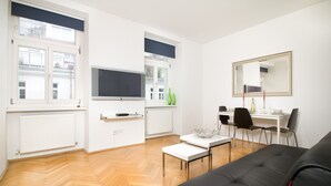 Una sala de estar moderna con un sofá negro, una mesa de centro blanca y un comedor con mesa y sillas.