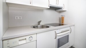 Una cocina con armarios blancos, un lavamanos doble, horno empotrado y lavavajillas.