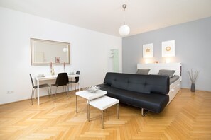 A modern living room with a sofa, a dining table, and a workspace.