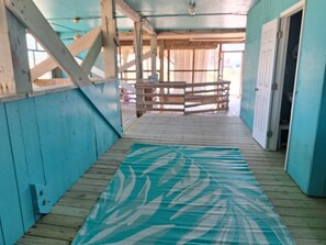 Une terrasse en bois avec un tapis à motifs, une rambarde en bois et une porte.