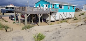 Une maison de plage dotée d’une terrasse en bois et d’un espace abrité.
