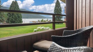 Een balkon met rieten stoelen en uitzicht op een meer en bergen.