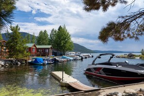 Un molo sul lago con barche, un pontile di legno e una cabina con tetto verde.