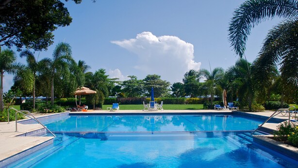 A clear blue swimming pool with lounge chairs and a gazebo. - Palm Beach 109 Hastings Barbados, 3 Bdrm condo. Beachfront, Pool, Best location! (Hastings)