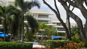 A hotel with multiple balconies, a swimming pool, and lush greenery. - Palm Beach 109 Hastings Barbados, 3 Bdrm condo. Beachfront, Pool, Best location! (Hastings)