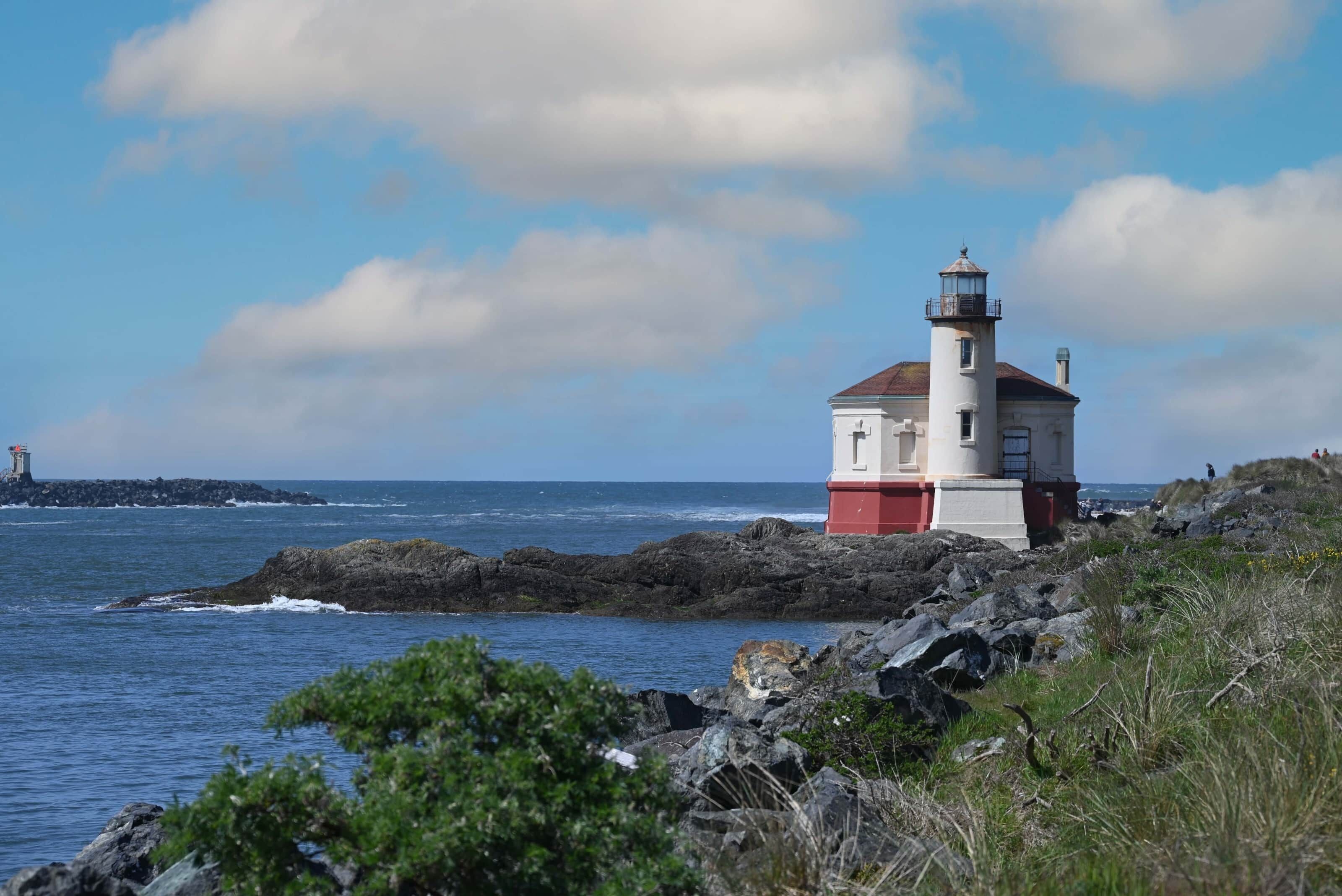 A lighthouse on a rocky shore with clear skies.