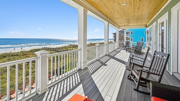 Una terraza de madera con mobiliario exterior con vistas a una playa.