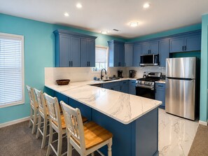 A kitchen with blue cabinets, a marble island, a stainless steel refrigerator, and a gas stove. - Ocean Views, Steps To Beach, and Close To Everything! (Wildwood Crest)