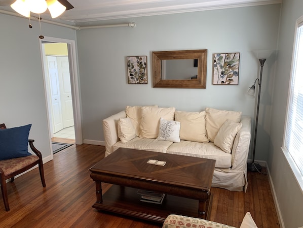 A living room with a beige sofa, a wooden coffee table, a blue chair, and a floor lamp.