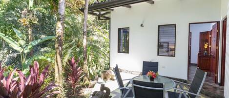Une terrasse avec une table et des chaises, entourée de plantes tropicales et agrémentée d’une sculpture d’éléphant en pierre.
