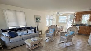 A spacious living room with a grey sofa, wicker rocking chairs, and a coffee table.