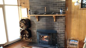 A cozy living room with a fireplace, wooden furniture, and a brick wall.