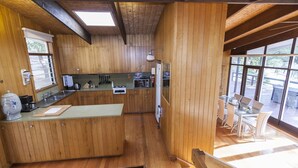 A kitchen with wooden cabinets, a central island, and a dining area with a table and chairs.