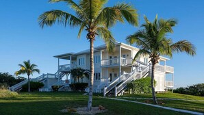 Ein mehrstöckiges Strandhotel mit weißer Fassade, mehreren Balkonen und einer Treppe, die zu den oberen Etagen führt.