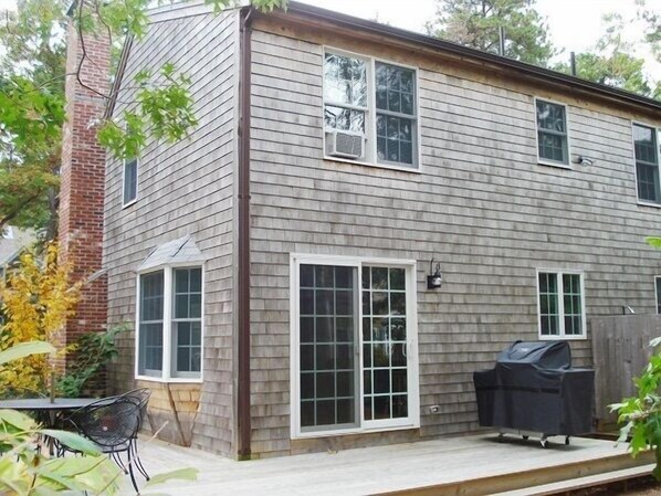 A two-story house with a brick chimney, large windows, and a deck with a grill. - 3 Bedroom Home .5 mile to Long Pond (1606) (Wellfleet)