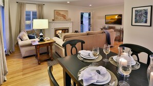 A well-lit living room with a fireplace, a dining area set for a meal, and a sofa. - Los Arboles Ranch - Recreational Dream Near Hope Ranch (Santa Barbara)
