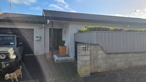 Ein Wohnhaus mit Garage, Auffahrt, einem kleinen Hund und einem Blumentopf.