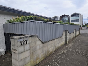 Un edificio residenziale con una recinzione in metallo grigio, un muro di cemento con il numero 127 e un'architettura moderna sullo sfondo.