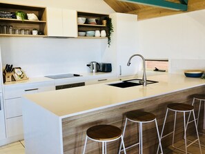 Une cuisine moderne dotée d’un grand îlot central, de tabourets de bar et d’un évier encastré.