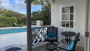 Eine überdachte Terrasse mit Pool, einer Glastür und Gartenmöbeln.