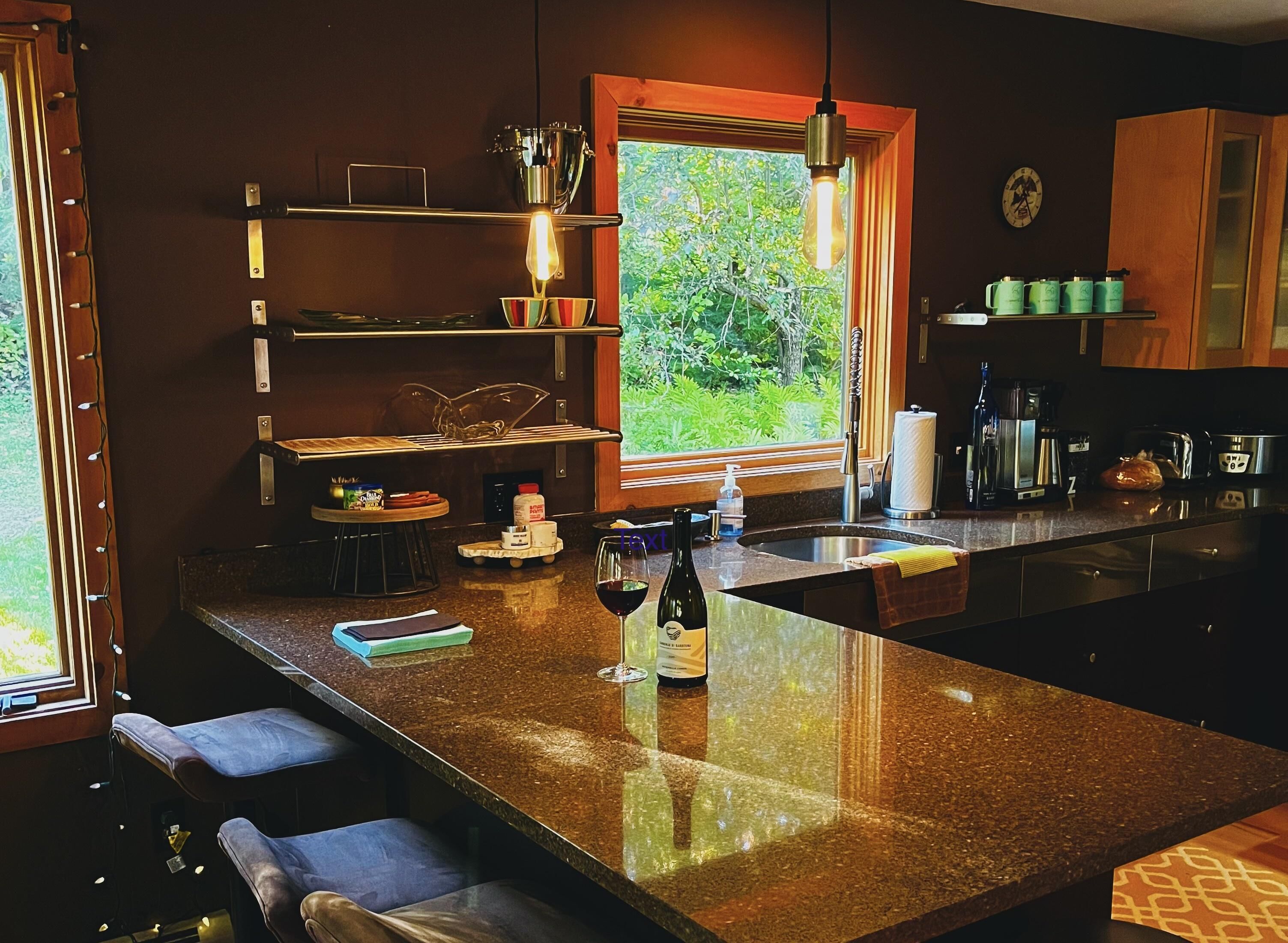 A modern kitchen with a granite countertop, a built-in sink, and a window overlooking greenery.