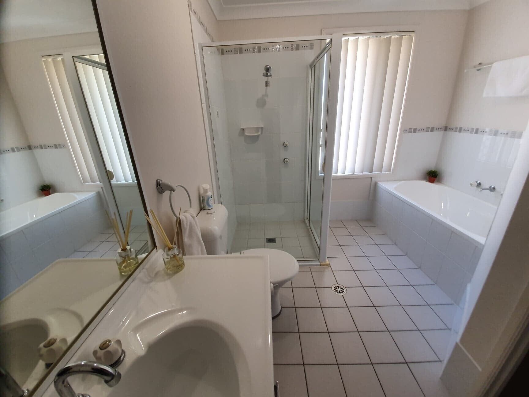 Ein modernes Badezimmer mit einer Dusche in Glasabtrennung, einem weißen Waschbecken und einer Badewanne.