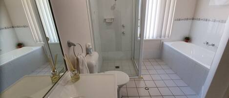 Ein modernes Badezimmer mit einer Dusche in Glasabtrennung, einem weißen Waschbecken und einer Badewanne.