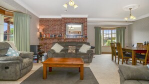 Una sala de estar con chimenea de ladrillo, un sofá, una mesa de centro y un comedor con sillas y una mesa.