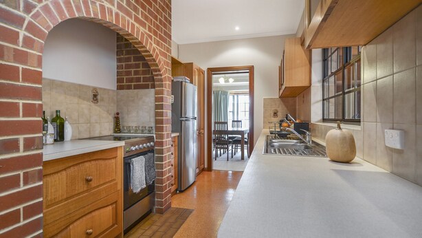 Una cocina con arco de ladrillo, electrodomésticos de acero inoxidable y un ventanal grande.