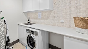 A laundry room with a washing machine, a sink, and a basket on the counter. - Beachfront #12 Beach Access, Pool, PetFriendly (Sapphire Beach)