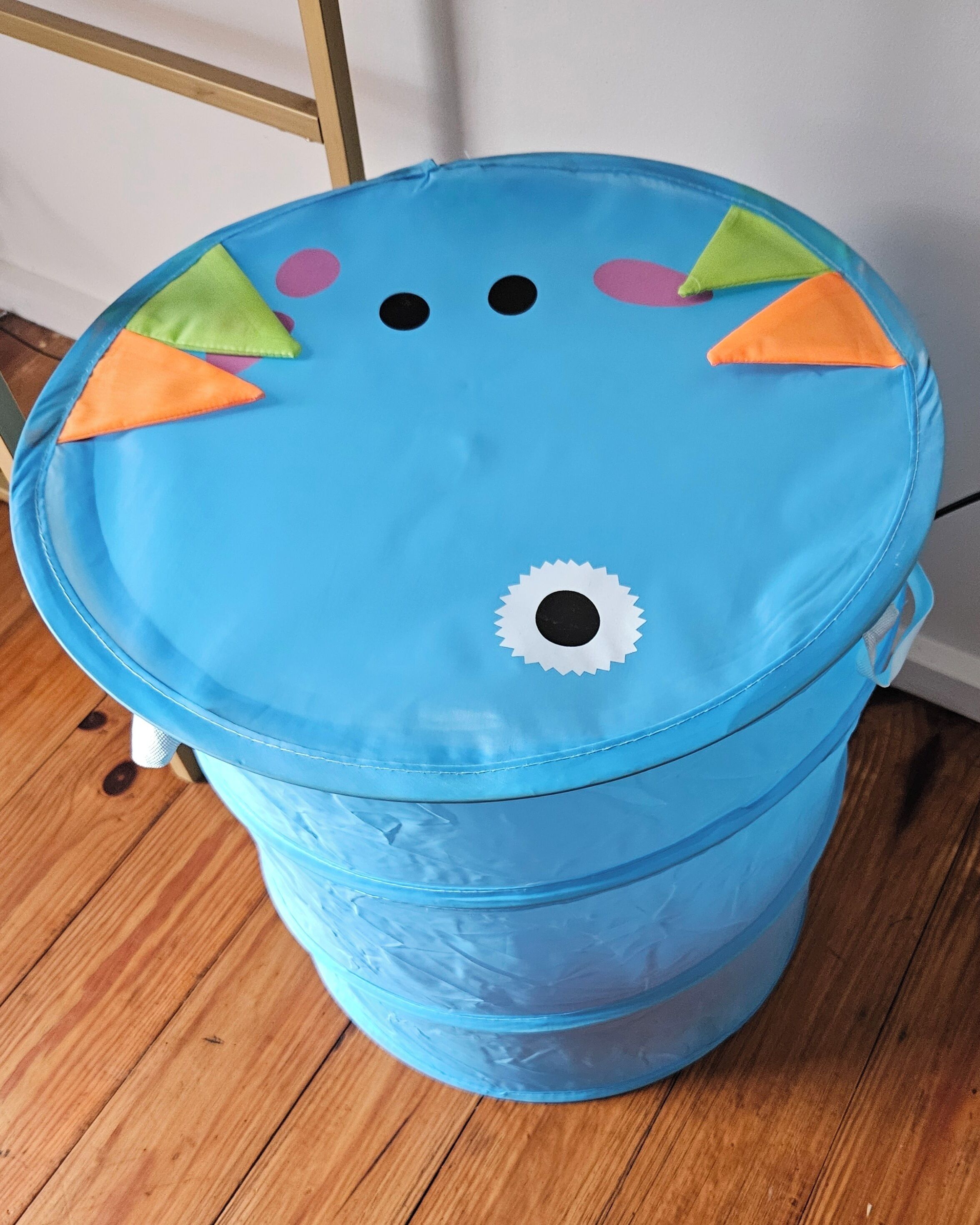A blue barrel with a lid decorated with colorful triangles and a white circular pattern.