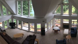 A spacious living room with large windows, a fireplace, and a dining area. - Czarnecky Home - Waterfront Home in Deerfield Resort, Dock, Hot Tub, Firepit (La Follette)