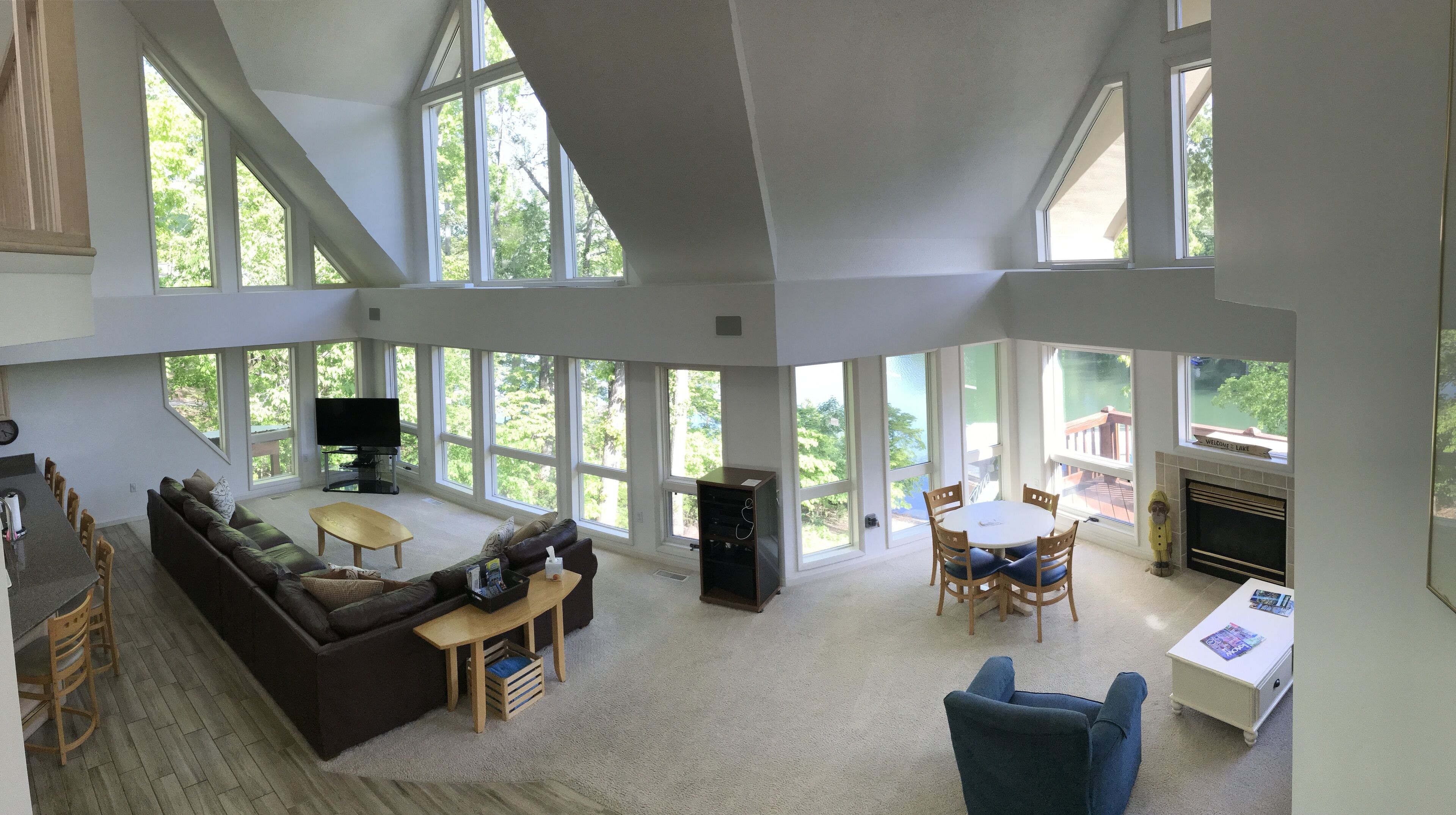 Ein geräumiges Wohnzimmer mit großem Fenster, Kamin und Fernseher.