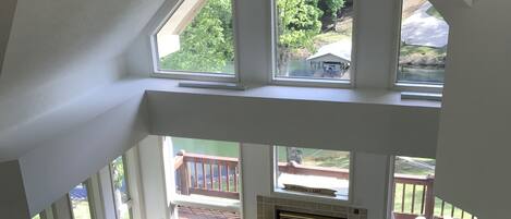 Un loft spacieux avec de hauts plafonds, de grandes fenêtres, un coin repas avec une table ronde et des chaises, une cheminée et un coin salon confortable avec un canapé bleu.