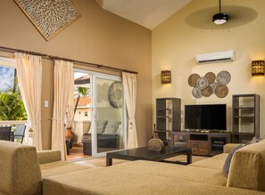 A living room with a sofa, TV, and decorative wall pieces.