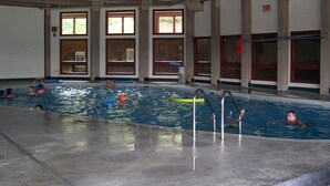 An indoor swimming pool with multiple lanes, a diving board, and a lifeguard chair.