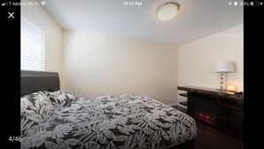 A bedroom with a bed, a nightstand, a lamp, and a fireplace. - Private Guest house close to Disneyland & Little Saigon Mall (Santa Ana)
