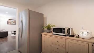 Una cocina con refrigerador de acero inoxidable, microondas, tostadora y un armario de madera.