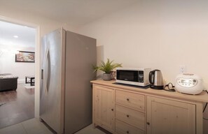 Una cocina con refrigerador de acero inoxidable, microondas, tostadora y un armario de madera.