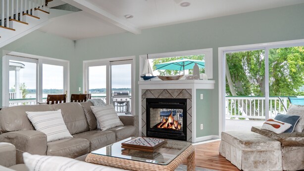 A living room with a fireplace, a sofa, a coffee table, and a view of the outdoors. - Private Beach & Pier Lake Front w/ Fireplace on Lake Como - Walk to Mars Resort! (Lake Geneva)