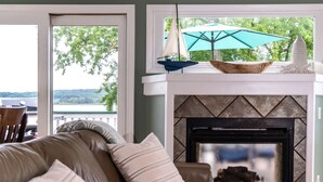 A living room with a leather sofa, a fireplace, and a view of the outdoors. - Private Beach & Pier Lake Front w/ Fireplace on Lake Como - Walk to Mars Resort! (Lake Geneva)