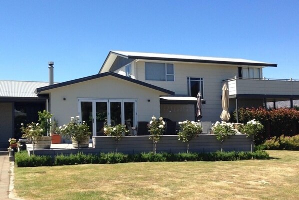 A modern two-story house with a flat roof, large windows, and a covered patio area. - Large Sunny Holiday Home (Wanaka)