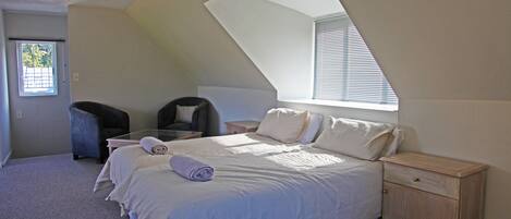 A bedroom with a large bed, a nightstand, a chair, and a ceiling fan.